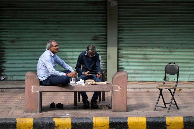 Security guards eat their breakfast in front of closed shops amid ongoing protests demanding the resignation of India's Chief Election Commissioner Gyanesh Kumar over alleged voter roll irregularities linked to the "special intensive revision" (SIR), near Jantar Mantar in New Delhi on October 11, 2026. (Photo by Sajjad HUSSAIN / AFP)