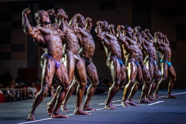 Competitor in the Men's Open Bodybuilding category strike poses on stage during the 2026 Body Fuel International Fitness Championship in Nairobi on October 10, 2026. The 2026 Body Fuel Fitness Championship brought together athletes from across Africa and beyond, highlighting the growing popularity of bodybuilding and competitive fitness on the continent. (Photo by Luis TATO / AFP)