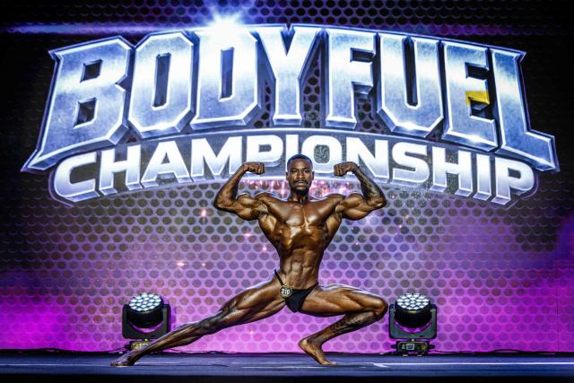 A competitor strikes poses on stage during the 2026 Body Fuel International Fitness Championship in Nairobi on October 10, 2026. The 2026 Body Fuel Fitness Championship brought together athletes from across Africa and beyond, highlighting the growing popularity of bodybuilding and competitive fitness on the continent. (Photo by Luis TATO / AFP)
