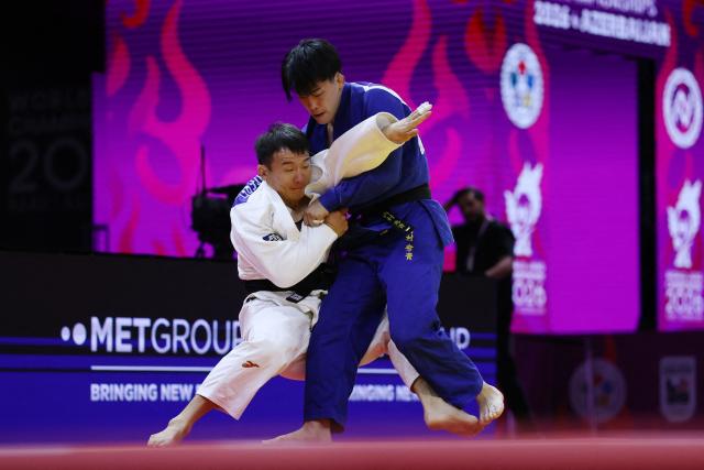Mongolia's Uranbayar Odgerel (white) competes against Japan's Shusuke Uchimura in the mixed team quarter-final at the World Judo Championships in Baku on October 11, 2026. (Photo by Anne-Christine POUJOULAT / AFP)