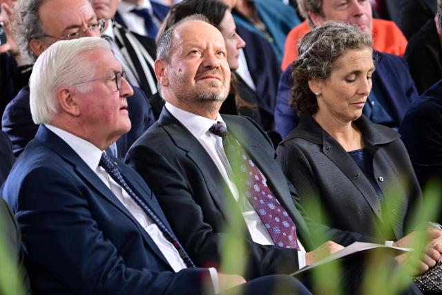 Laureate British-French lawyer and writer Philippe Sands (C) looks on next to his wife Natalia Schiffrin (R) and German President Frank-Walter Steinmeier during the awarding ceremony for the 2026 Peace Prize of the German Book Trade at the St Paul's Church in Frankfurt am Main, western Germany on October 11, 2026. In its statement, the jury wrote: 'As one of the most important intellectual voices of our time, the French-British lawyer and writer advocates for justice, peace, and the steadfast defense of international law. A descendant of Holocaust survivors, he uses his own family history to show how this body of law came into being and what experiences lie behind the legal concepts of 'genocide' and 'crimes against humanity'.' (Photo by Thomas Lohnes / POOL / AFP)