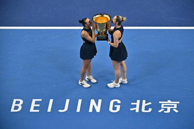 Brazil’s Luisa Stefani (L) and Canada’s Gabriela Dabrowski kiss the trophy after beating Czech Republic’s Katerina Siniakova and China’s Zhang Shuai in the women’s doubles final at the China Open tennis tournament in Beijing on October 11, 2026. (Photo by PEDRO PARDO / AFP)