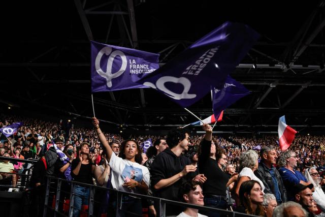 Supporters wave party flags as they attend the Leftist party La France Insoumise (LFI) candidate in France's 2027 presidential election Jean-Luc Melenchon's campaign rally for the 2027 presidential election at the Zenith concert hall in Cournon-d’Auvergne on October 11, 2026. (Photo by JEFF PACHOUD / AFP)