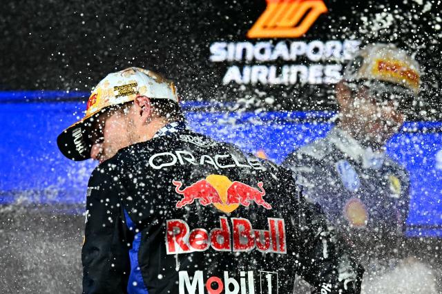 Winner Red Bull Racing's Dutch driver Max Verstappen (L) and second-placed Ferrari's Monegasque driver Charles Leclerc celebrate on the podium after the Formula One Singapore Grand Prix at the Marina Bay Street Circuit in Singapore on October 11, 2026. (Photo by Lillian SUWANRUMPHA / AFP)