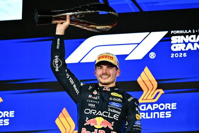 Winner Red Bull Racing's Dutch driver Max Verstappen lifts his trophy as he celebrates on the podium after the Formula One Singapore Grand Prix at the Marina Bay Street Circuit in Singapore on October 11, 2026. (Photo by Lillian SUWANRUMPHA / AFP)