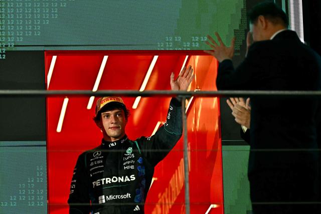 Third-placed Mercedes' Italian driver Kimi Antonelli (L) waves to supportes as he celebrates on the podium after the Formula One Singapore Grand Prix at the Marina Bay Street Circuit in Singapore on October 11, 2026. (Photo by Lillian SUWANRUMPHA / AFP)