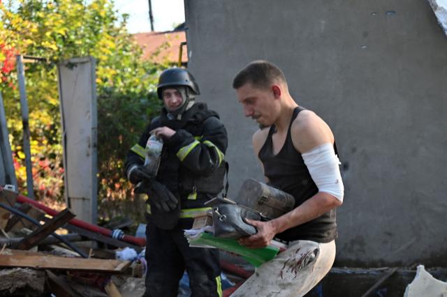 A local resident carries documents found in the ruins of private houses destroyed following a Russian guided aerial bomb attack that killed one person, amid the Russian invasion of Ukraine, in Kharkiv on October 11, 2026. (Photo by SERGEY BOBOK / AFP)