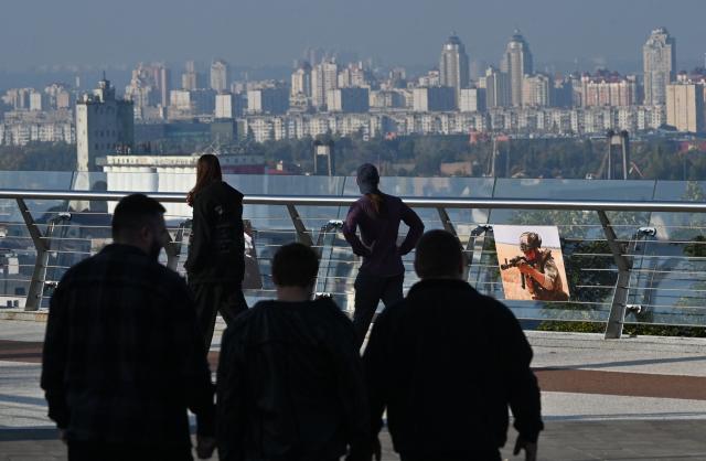 People walk past a photograph depicting Ukrainian serviceman at open air photo exhibition in Kyiv on October 11, 2026, amid Russian invasion in Ukraine. (Photo by Sergei SUPINSKY / AFP)