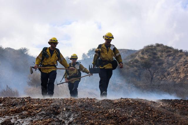 Firefighters walk to a ridge while fighting the Bike fire in the outskirts of Santa Clarita, California on October 11, 2026. Los Angeles County Fire is battling a fast moving wildfire that started on Sunday afternoon threatening homes in Santa Clarita, the third largest city in Los Angeles County. The LA County Sheriff's office ordered residents to evacuate as the Bike fire grew to 100 acres in size in a very short time. (Photo by David Swanson / AFP)