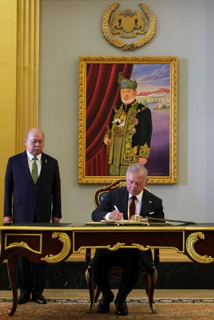 Jordan's King Abdullah II writes in a guest book next to Malaysia's King Sultan Ibrahim Sultan Iskandar at the National Palace in Kuala Lumpur on October 12, 2026. (Photo by Hasnoor Hussain / POOL / AFP)