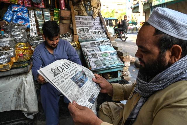 People read newspapers at a roadside stall after the imposition of an emergency rule in Peshawar on October 12, 2026 following anti-government demonstrations by the opposition Pakistan Tehreek-e-Insaf (PTI) party demanding the release of jailed former prime minister Imran Khan. Pakistan placed a northern province under emergency rule on October 11, the president's office said, following anti-government demonstrations by supporters of jailed former prime minister Imran Khan and militant violence in the northwest. (Photo by Abdul MAJEED / AFP)