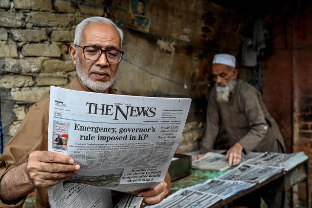 A man reads a newspaper with the coverage of imposition of an emergency rule by the government in Peshawar on October 12, 2026, following anti-government demonstrations by the opposition Pakistan Tehreek-e-Insaf (PTI) party demanding the release of jailed former prime minister Imran Khan. Pakistan placed a northern province under emergency rule on October 11, the president's office said, following anti-government demonstrations by supporters of jailed former prime minister Imran Khan and militant violence in the northwest. (Photo by Abdul MAJEED / AFP)