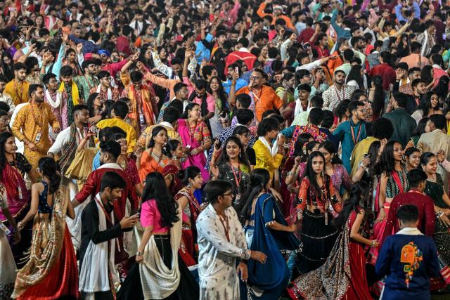 People wearing traditional dresses perform the 'Garba' dance as part of the annual Hindu festival of Navratri at the Laxmi Vilas Palace in Vadodara on October 11, 2026. (Photo by Noah SEELAM / AFP)