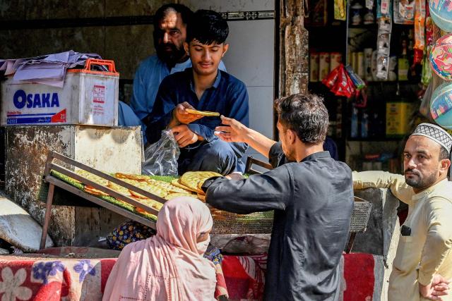 People buy breads at a bakery shop after the imposition of an emergency rule in Peshawar on October 12, 2026 following anti-government demonstrations by the opposition Pakistan Tehreek-e-Insaf (PTI) party demanding the release of jailed former prime minister Imran Khan. Pakistan placed a northern province under emergency rule on October 11, the president's office said, following anti-government demonstrations by supporters of jailed former prime minister Imran Khan and militant violence in the northwest. (Photo by Abdul MAJEED / AFP)