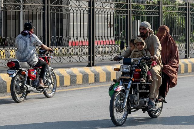 People travel along a road after the imposition of an emergency rule in Peshawar on October 12, 2026 following anti-government demonstrations by the opposition Pakistan Tehreek-e-Insaf (PTI) party demanding the release of jailed former prime minister Imran Khan. Pakistan placed a northern province under emergency rule on October 11, the president's office said, following anti-government demonstrations by supporters of jailed former prime minister Imran Khan and militant violence in the northwest. (Photo by Abdul MAJEED / AFP)