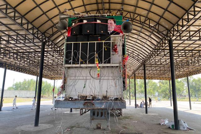 People are seen near an abandoned container truck which was used by inactive Khyber Pakhtunkhwa chief minister Muhammad Sohail Afridi during a protest march organised by the Pakistan Tehreek-e-Insaf (PTI) party to demand the release of jailed former prime minister Imran Khan, at a bus terminal in Mardan on October 12, 2026. Pakistan placed a northern province under emergency rule on October 11, the president's office said, following anti-government demonstrations by supporters of jailed former prime minister Imran Khan and militant violence in the northwest. (Photo by AFP)