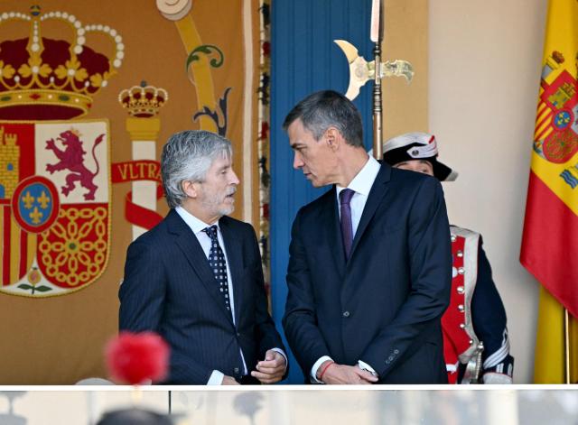 Prime Minister Pedro Sanchez (R) talks with Spain's Interior Minister Fernando Grande Marlaska during Spain's National Day military parade in Madrid, on October 12, 2026. (Photo by JAVIER SORIANO / AFP)