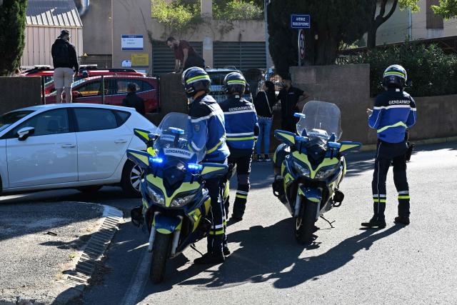 French gendarmes stand in front of Joseph-Lakanal high school after a headmaster was injured by a hunting rifle shot and a teenager was arrested in Aubagne, southern France, on October 12, 2026. The school head was hit by a 12-gauge hunting rifle shot, a source specified, adding that a member of the teaching staff was also hit. The victim's life is not in danger. (Photo by Miguel MEDINA / AFP)