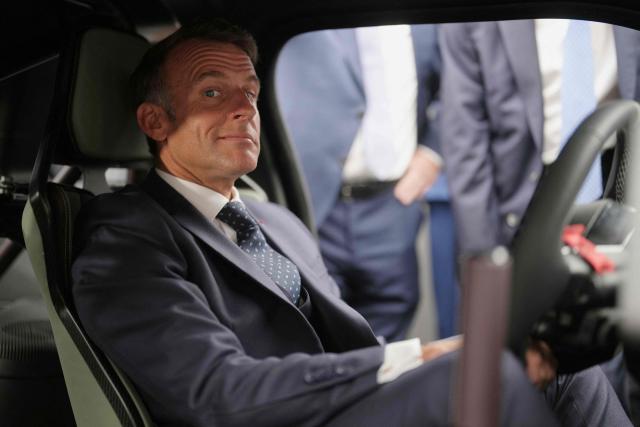 France's President Emmanuel Macron sits inside a Renault 5 Turbo 3E car as he visits Renault stand aduring the international Paris Motor Show at the Porte de Versailles in Paris on October 12, 2026. (Photo by Thibault Camus / POOL / AFP)