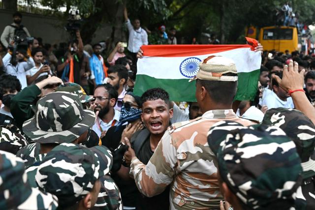 A supporter of India's opposition Congress party holds the country's national flag as he scuffles with security personnel during a protest demanding the resignation of the nation's Chief Election Commissioner Gyanesh Kumar over alleged voter roll irregularities linked to the "special intensive revision" (SIR), in New Delhi on October 12, 2026. Authorities deployed thousands of personnel across central Delhi for a third straight day on October 12, erecting heavy metal barricades and closing key metro stations before a march called by opposition leader Rahul Gandhi. (Photo by Sajjad HUSSAIN / AFP)
