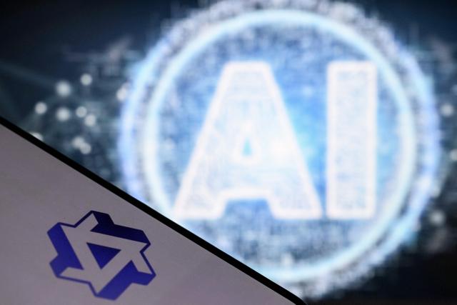 A photo taken on October 12, 2026 shows AI letters on a laptop screen next to the logo of China's Tongyi Qianwen AI application (bottom) by Alibaba group on a smartphone screen in Frankfurt am Main, western Germany. (Photo by Kirill KUDRYAVTSEV / AFP)