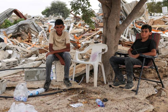 Boys sit by the rubble of the destroyed buildings of the Abu Wadi Bedouin community that were demolished for lack of construction permits, in the village of al-Dhahiyah near Rahat in Israel's southern district on October 12, 2026. Israeli authorities on October 12 demolished 80 homes and a mosque, displacing approximately 400 residents of the village in the Negev desert in southern Israel, according to the mayor of Rahat and local residents. (Photo by AHMAD GHARABLI / AFP)