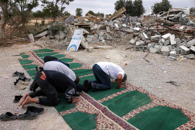 TOPSHOT - The local mosque imam leads a few worshippers in prayer by the rubble of the destroyed mosque building that was demolished along with others of the Abu Wadi Bedouin community for lack of construction permits, in the village of al-Dhahiyah near Rahat in Israel's southern district on October 12, 2026. Israeli authorities on October 12 demolished 80 homes and a mosque, displacing approximately 400 residents of the village in the Negev desert in southern Israel, according to the mayor of Rahat and local residents. (Photo by AHMAD GHARABLI / AFP)