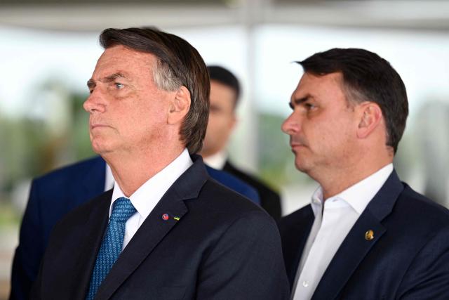 (FILES) Brazilian President and re-election candidate Jair Bolsonaro (L) listens to questions next to his son Flavio during a press conference at Planalto Palace in Brasilia, on October 4, 2022. Brazil's Supreme Court authorised on October 12, 2026, presidential candidate Flavio Bolsonaro to resume visiting his father, former president Jair Bolsonaro, who is under house arrest, provided the visits do not involve electoral campaign activities ahead of the second round of Brazil's presidential election. (Photo by EVARISTO SA / AFP)