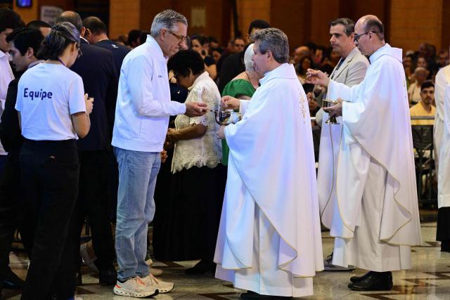 Brazil's Health Minister Alexandre Padilha receives communion during a mass marking the celebration of Brazil's patron saint, Our Lady of Aparecida, at the National Shrine of Our Lady of Aparecida in Aparecida, Sao Paulo state, Brazil, on October 12, 2026. (Photo by Pablo PORCIUNCULA / AFP)