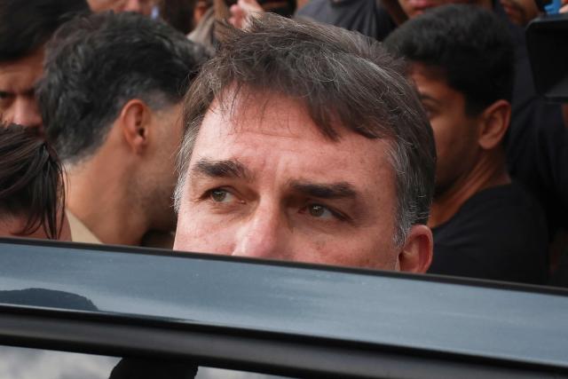 Brazil's right-wing Senator and presidential candidate for the Liberal Party (PL) Flavio Bolsonaro gives the thumbs-up as he leaves following a mass marking the celebration of Brazil's patron saint, Our Lady of Aparecida, at the Metropolitan Cathedral of Brasilia in Brasilia, Brazil, on October 12, 2026. (Photo by Sergio Lima / AFP)