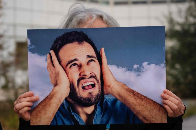 A protester holds a placard during a rally organised by the "Rester sur Terre" network and non-profit organization ADVOCNAR, to protest against the project to extend the Paris Charles de Gaulle Airport, in Roissy-en-France, near Paris on October 12, 2026. (Photo by Dimitar DILKOFF / AFP)
