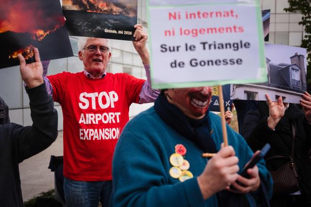 Protesters hold placard during a rally organised by the "Rester sur Terre" network and non-profit organization ADVOCNAR, to protest against the project to extend the Paris Charles de Gaulle Airport, in Roissy-en-France, near Paris on October 12, 2026. (Photo by Dimitar DILKOFF / AFP)