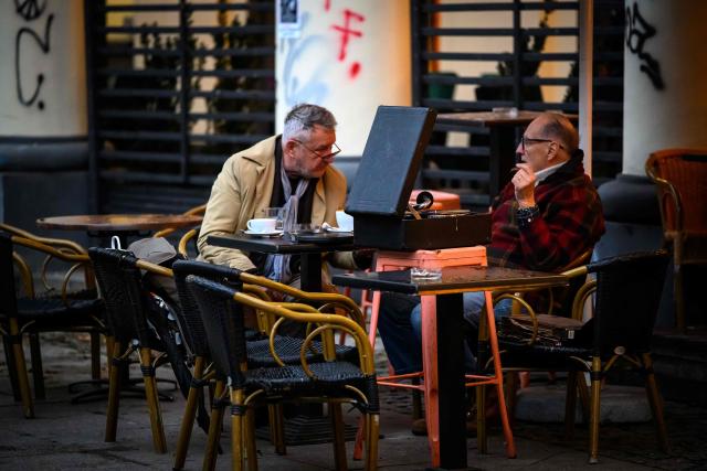 Locals listen to an old turntable while drinking coffee in downtown Warsaw on October 12, 2026. (Photo by Mladen ANTONOV / AFP)