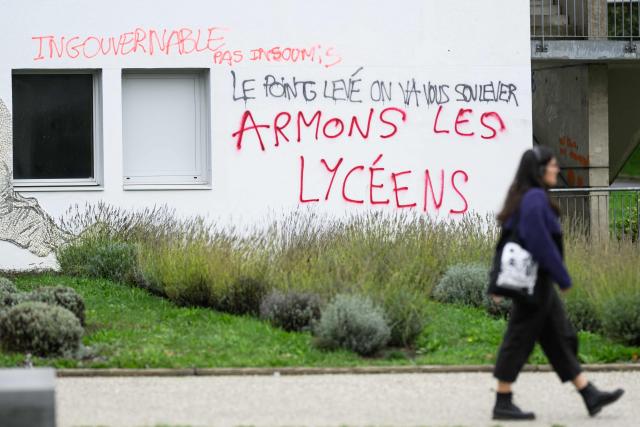 A student passes by a graffiti readin"Let’s arm high school pupils" wall of a building in the Rennes 2 university, on october 12, 2026. (Photo by Loic VENANCE / AFP)