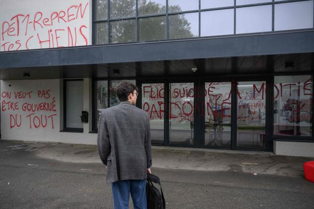 A student walks past a graffiti reading "We don’t want to be governed at all" (L) on a wall of a building in the Rennes 2 university, on october 12, 2026. (Photo by Loic VENANCE / AFP)