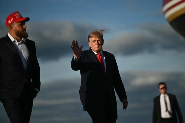 US President Donald Trump waves alongside US boxer and influencer Jake Paul before boarding Air Force One at Joint Base Andrews, Maryland, on October 12, 2026. President Trump is traveling to Youngstown, Ohio, to hold a campaign rally ahead of the midterm elections. (Photo by Kent NISHIMURA / AFP)