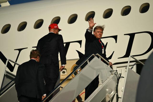 US President Donald Trump waves alongside US boxer and influencer Jake Paul as they board Air Force One at Joint Base Andrews, Maryland, on October 12, 2026. Trump is traveling to Youngstown, Ohio, to hold a campaign rally ahead of the midterm elections. (Photo by Kent NISHIMURA / AFP)
