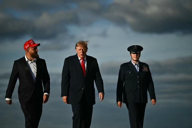 US President Donald Trump waves alongside US boxer and influencer Jake Paul before boarding Air Force One at Joint Base Andrews, Maryland, on October 12, 2026. President Trump is traveling to Youngstown, Ohio, to hold a campaign rally ahead of the midterm elections. (Photo by Kent NISHIMURA / AFP)