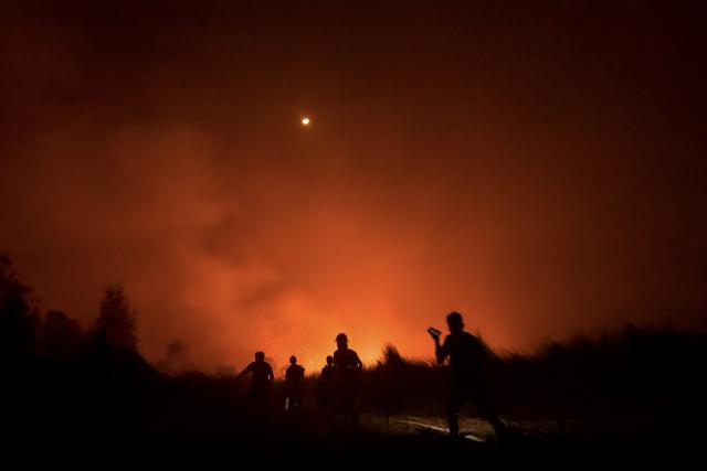 (FILES) Local residents and volunteers of the local fire brigade battle a peatland fire at Gambut village in Banjar, South Kalimantan on October 2, 2026. For weeks on end, parts of Indonesian Borneo have resembled an Armageddon landscape with masked residents immersed in a putrid, red-brown haze as wildfires devour peatlands near homes and farms. Burning slowly, mostly under the surface and sometimes for months on end, peatland fires are responsible for much of the dry season haze that this year has tainted air as far afield as Malaysia, Singapore and the Philippines. (Photo by MUDA SAGALA / AFP) / To go with AFP story Indonesia-environment-climate-fire-peatland, FACTS by Mariette Le Roux
