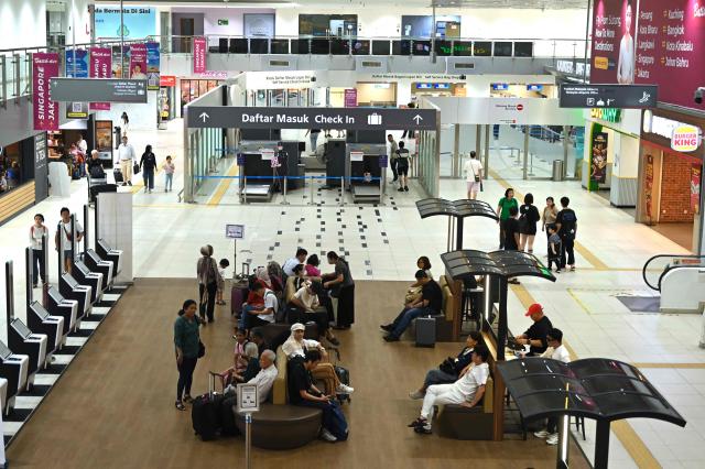 Passengers wait for their flights at Sultan Abdul Aziz Shah Airport in Subang, Selangor state, on October 13, 2026. Malaysian low-cost carrier Firefly has extended flight cancellations between Kuala Lumpur and Singapore until October 14, the airline said, as haze from fires in neighbouring Indonesia chokes air quality across the region. (Photo by Mohd RASFAN / AFP)