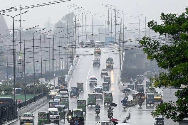 Commuters travel along a road amid heavy rain in Peshawar on October 13, 2026. (Photo by Abdul MAJEED / AFP)