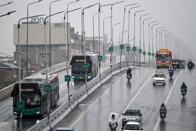 Commuters travel along a road amid heavy rain in Peshawar on October 13, 2026. (Photo by Abdul MAJEED / AFP)