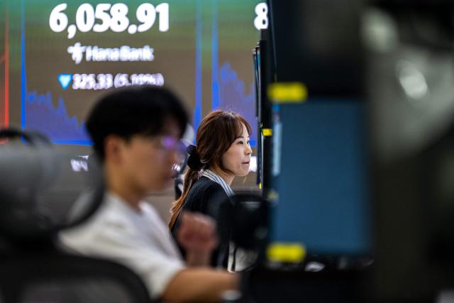 Dealers work near an electronic screen showing South Korea's benchmark stock index (KOSPI) in a dealing room at the Hana Bank headquarters in Seoul on October 13, 2026. Seoul, Tokyo and Taipei led losses across Asian stock markets on October 13 as technology firms plunged on fresh worries about the outlook for the AI investment boom, with traders preparing for a crucial earnings season and release of key US data. (Photo by Philip FONG / AFP)