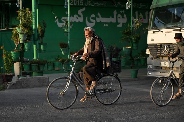 An elderly Afghan man rides a bicycle along a road in Kandahar on October 13, 2026. (Photo by Sanaullah SEIAM / AFP)