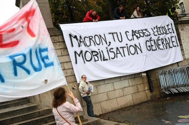 People install a banner which reads as 'Macron, You break scholl! General mobilization!' ahead of the start of a demonstration of high-school students in Nantes, western France on October 13, 2026, as part of a nationwide high school mobilisation over learning conditions. France sees nationwide demonstrations on October 13 in support of students protesting poor classroom conditions for weeks, as authorities and participants remain wary of further violence. (Photo by Sebastien Salom-Gomis / AFP)