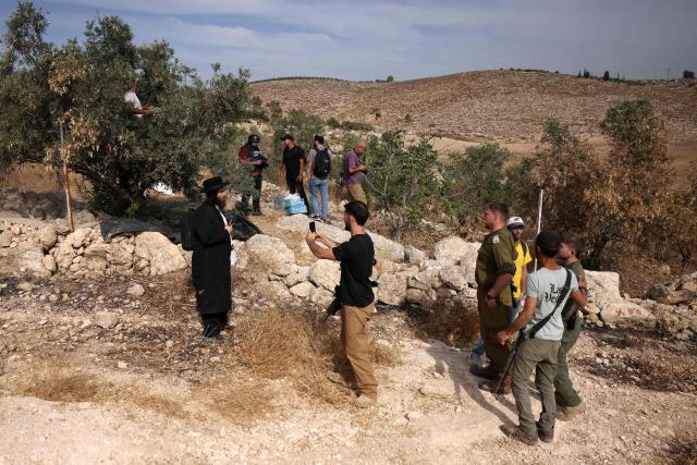 Israeli security forces and armed settlers evacuate Palestinians and Israeli activists from the area of olive tree plantation in Idna village near the occupied West Bank town of Hebron, on October 13, 2026. The olive harvest starts in the West Bank in October and makes up a large component of the agricultural economy and cultural life for most Palestinians. Extremist Israeli settlers have been seizing olive groves owned by Palestinians, who see the trees as a cultural symbol. The olive harvest is a major component of the West Banks agricultural economy, rural livelihoods and cultural life. (Photo by HAZEM BADER / AFP)