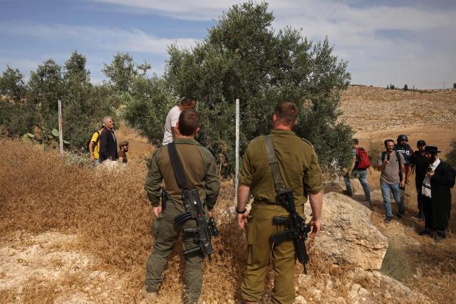 Israeli security forces and armed settlers evacuate Palestinians and Israeli activists from the area of olive tree plantation in Idna village near the occupied West Bank town of Hebron, on October 13, 2026. The olive harvest starts in the West Bank in October and makes up a large component of the agricultural economy and cultural life for most Palestinians. Extremist Israeli settlers have been seizing olive groves owned by Palestinians, who see the trees as a cultural symbol. The olive harvest is a major component of the West Banks agricultural economy, rural livelihoods and cultural life. (Photo by HAZEM BADER / AFP)