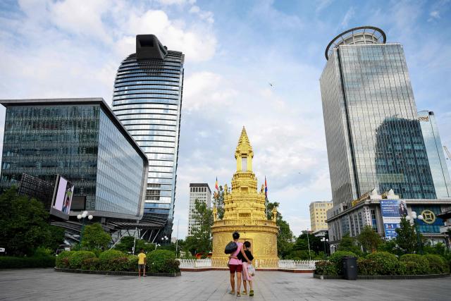 A woman and her daughter walk in front of the Buddha stupa in Phnom Penh on October 13, 2026. (Photo by TANG CHHIN Sothy / AFP)