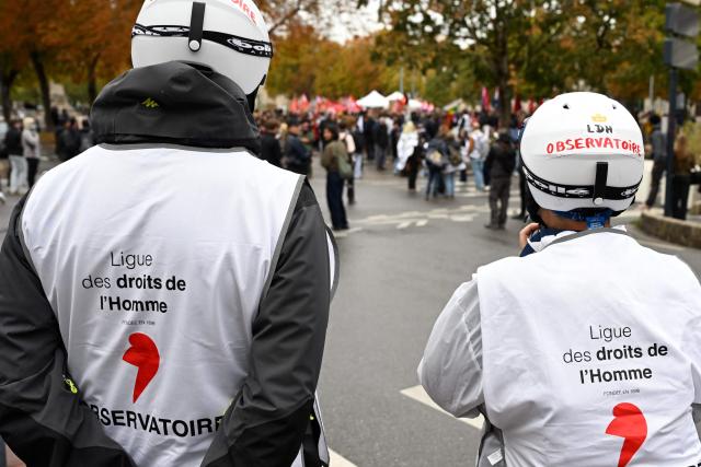 Volunteers of the "Human rights league" watch protesters during a demonstration of high-school students in Nancy, northeastern France on October 13, 2026, as part of a nationwide high school mobilisation. France sees nationwide demonstrations on October 13 in support of students protesting poor classroom conditions for weeks, as authorities and participants remain wary of further violence. (Photo by Jean-Christophe VERHAEGEN / AFP)