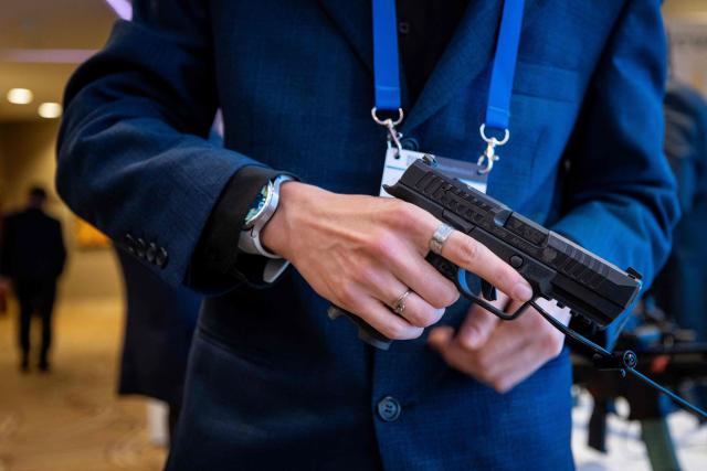 A participant inspects a weapon displayed at a stand during the second day of Warsaw Security Forum in Warsaw, Poland on October 13, 2026. (Photo by Wojtek RADWANSKI / AFP)